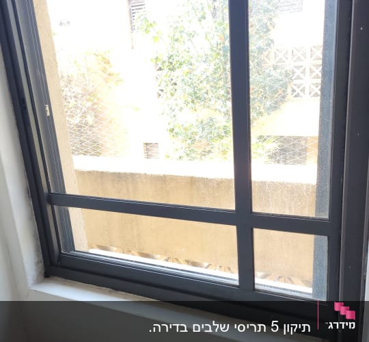 חלון עם תריסים שחורים פתוחים למחצה